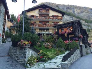 un bâtiment avec des fleurs devant lui dans l'établissement Hotel Romantica, à Zermatt