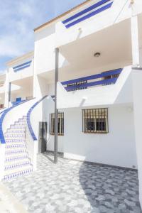 a white building with blue stairs in front of it at Playa de Peñíscola - Ideal familias 6-7 pax o Parejas 2-4 pax - terraza - parking in Peniscola +29 photos