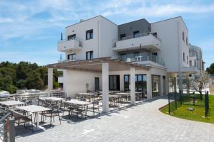 a large white building with tables and chairs at Apartments Flora in Premantura