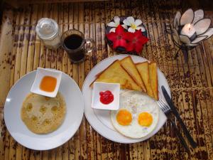 two plates with eggs and toast on a table at Relaxing Homestay & Hostel in Kuta Lombok +65 photos