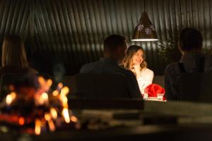 una mujer sentada en una mesa frente a una chimenea en Hotel Vartiosaari The Aurora Island, en Rovaniemi