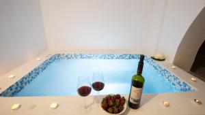 a bottle of wine and wine glasses next to a swimming pool at Villa Libertad in Imerovigli