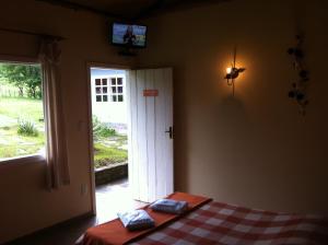 um quarto com uma cama e uma porta com uma televisão em Pousada Tabuleiro Eco em Conceição do Mato Dentro