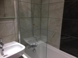 La salle de bains est pourvue d'une douche, d'un lavabo et d'une baignoire. dans l'établissement TW4 Apartments – Hounslow, à Hounslow