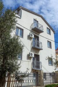 a white building with balconies and a fence at Apartments in city center Ventus in Novalja