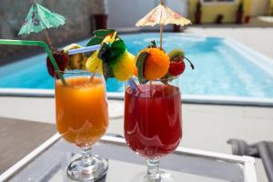 two cocktails sitting on a table next to a swimming pool at Villa Libertad in Imerovigli