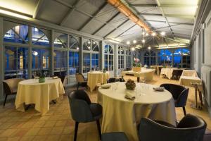 un restaurante con mesas y sillas blancas y ventanas en Relais Sant'Uffizio Wellness & Spa en Cioccaro
