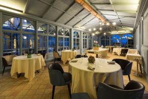 a restaurant with white tables and chairs and windows at Relais Sant'Uffizio Wellness & Spa in Cioccaro