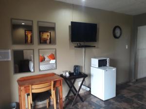 a living room with a tv and a table and a desk with a computer at Pepe Piatto Lodge in Grootvlei