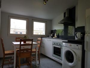 a kitchen with a washing machine and a table with chairs at Apartament Nowy Świat in Warsaw