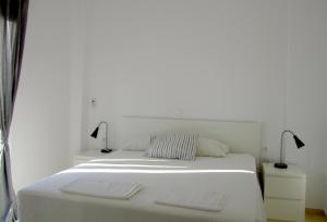 a white bed with two lamps on top of it at Helios Studios & Apartments in Makry Gialos