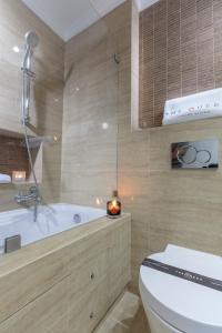 ein Badezimmer mit einem WC, einer Badewanne und einer Kerze in der Unterkunft The Queen Luxury Apartments - Villa Vinicia in Luxemburg (Stadt)