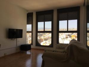 a living room with a couch and a tv and windows at Vacacional moderno nucleo Santa Cruz in Santa Cruz de Tenerife