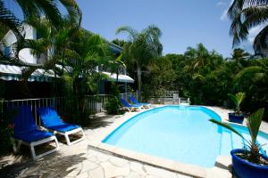 a swimming pool with blue chairs and palm trees at Résidence Bleu Marine in Le Gosier