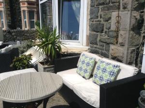 ławka z 2 poduszkami i stół na patio w obiekcie Endeavour Guest House w mieście Barmouth