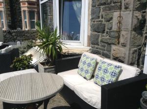 a bench with two pillows and a table on a patio at Endeavour Guest House in Barmouth