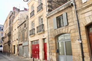 a row of buildings with red doors on a street at LE CONFIDENTIEL by Cocoonr in Bordeaux