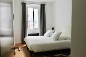 a bedroom with a bed with white sheets and a window at LE CONFIDENTIEL by Cocoonr in Bordeaux