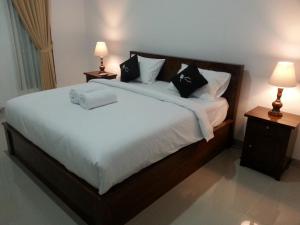 1 dormitorio con 1 cama grande con sábanas y almohadas blancas en Ega Homestay, en Nusa Penida
