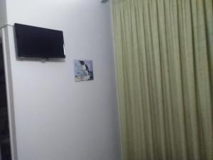 a television on a wall next to a green curtain at Pyrassos in Nea Anchialos