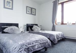 a bedroom with two beds and a window at Silver Tides House in Greenock