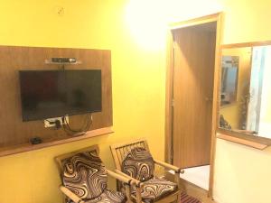 a living room with two chairs and a flat screen tv at Hotel Rattans Regency in Roorkee