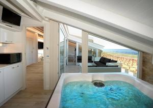 Opera Arte Suite Apartments في بورتو ريكاناتي: حوض استحمام كبير في غرفة مطلة