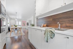 a kitchen with white cabinets and a wooden wall at Modern apartment Tromsø in Tromsø
