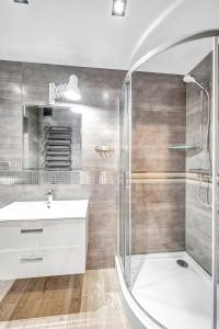 a bathroom with a shower and a sink and a tub at ORION Downtown Apartment by PinPoint in Łódź