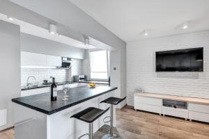 a white kitchen with a counter and two stools at ORION Downtown Apartment by PinPoint in Łódź