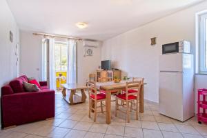 a kitchen and living room with a table and a refrigerator at Apartment Chiara Martinscica in Martinšćica