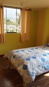 a bedroom with a bed with a comforter and a window at Los Geranios in Yanque