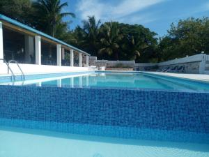 a swimming pool with blue tile in a resort at Hotel El Quemaito - Luxury Oceanfront Retreat in Santa Cruz de Barahona