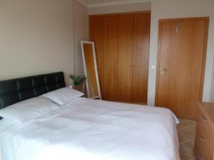 een slaapkamer met een groot wit bed en een houten kast bij Oceanic Apartment in Caniço
