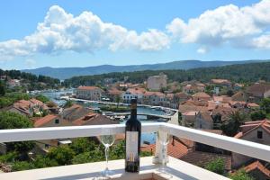 a bottle of wine sitting on a balcony with two wine glasses at Apartments Ena in Vrboska