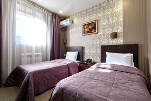 クラスノダールにあるHotel Altayのベッド2台と窓が備わるホテルルームです。