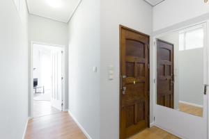 a hallway with white walls and a wooden door at Gaia Metro-2 Bedrooms in Vila Nova de Gaia