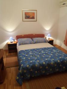 ein Schlafzimmer mit einem Bett mit einer blauen Bettdecke und zwei Lampen in der Unterkunft Apartman Zlatko in Zadar