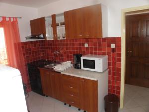 eine Küche mit einer Mikrowelle und roten Wandfliesen in der Unterkunft Apartman Zlatko in Zadar + 2 Fotos