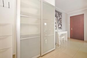 a white closet with glass shelves in a room at House Managers - Galeria in Gdańsk