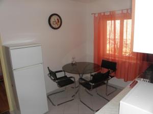 einen Tisch und Stühle in einer Küche mit einer Uhr an der Wand in der Unterkunft Apartman Zlatko in Zadar