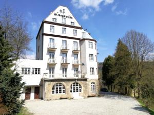 un grand bâtiment blanc avec une tour dans l'établissement Rezydencja Zamek, à Krynica-Zdrój