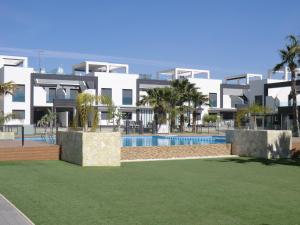 un gran edificio blanco con piscina y palmeras en Casas Holiday - Oasis Beach, en Playas de Orihuela