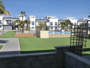 a lawn with palm trees in front of a building at Casas Holiday - Oasis Beach in Playas de Orihuela