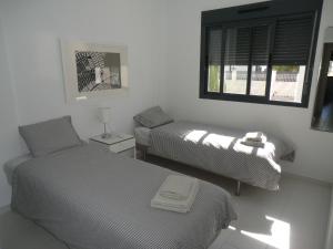 two beds in a white room with a window at Casas Holiday - Oasis Beach in Playas de Orihuela +28 photos