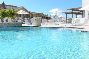 a large swimming pool with white chairs and umbrellas at Barefoot Beach Club in St. Pete Beach