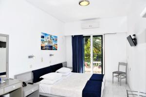 a white bedroom with a bed and a balcony at Anna Studios in Pythagoreio