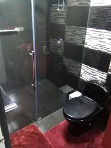 a bathroom with a black toilet and a glass shower at Mi casa es su casa in Lima