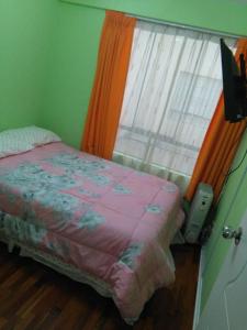 a bedroom with a bed next to a window at Mi casa es su casa in Lima