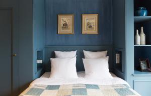 1 dormitorio con paredes azules y 1 cama con almohadas blancas en Suitehotel Posthoorn en Monnickendam